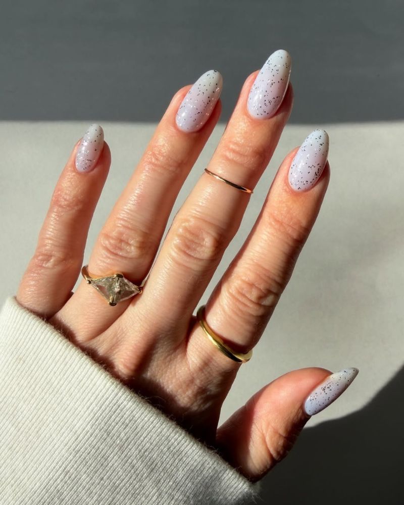 milky white nails with silver sparkles on an almond shape