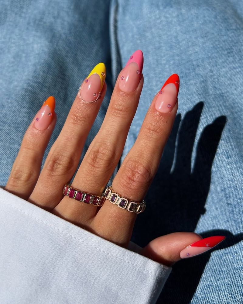 neon french tip nails in warm shades from yellow to red with pink rhinestone dot accents on almond nails