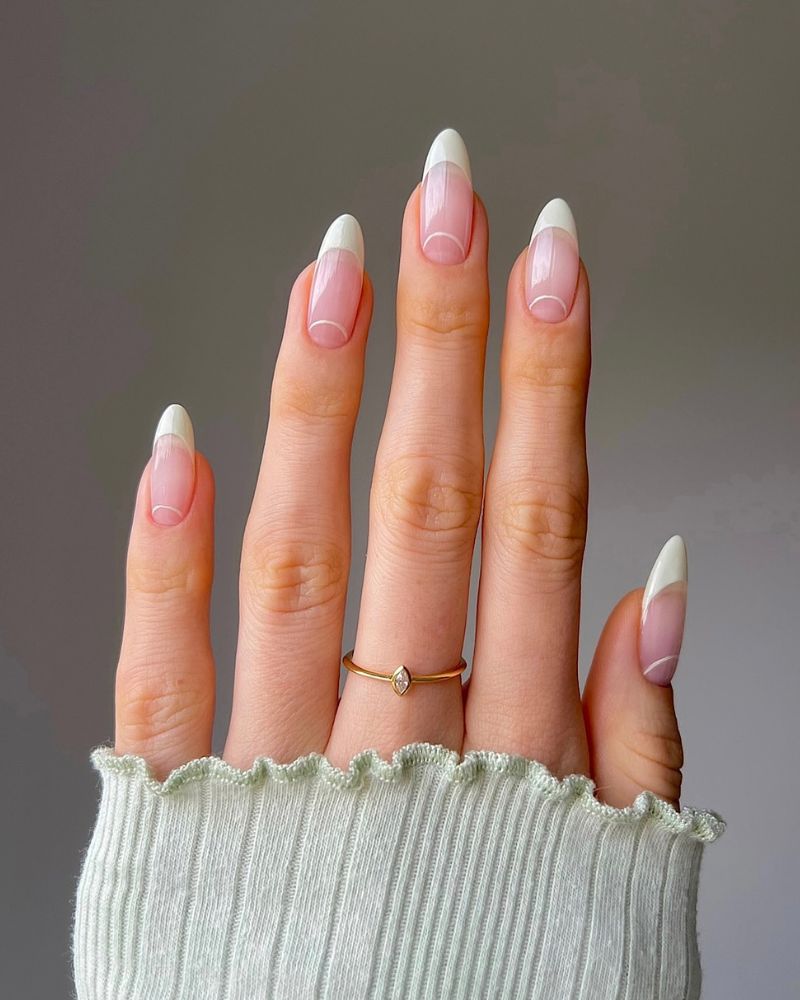 classic white french tip nails with delicate white flower painted on the accent nail almond shape
