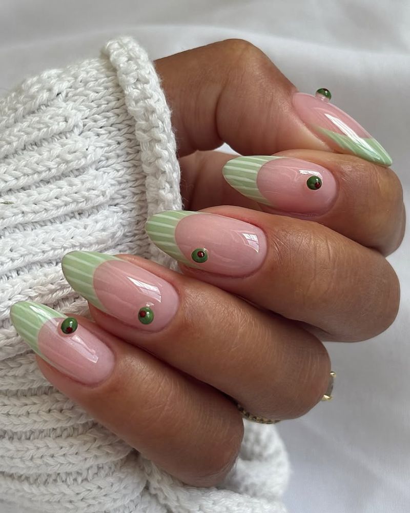 sage green striped french tips with small gem accents centered on the nail body almond nails