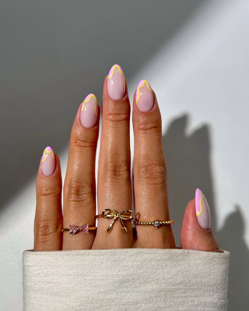 soft pink base french tip nails with bubbly yellow wave outline on almond nails