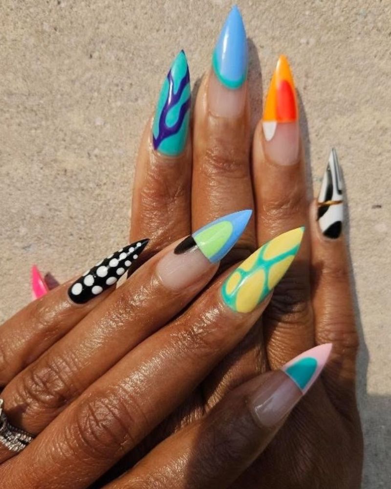 long stiletto nails with bold graphic patterns including flames, zebra print, and color blocks
