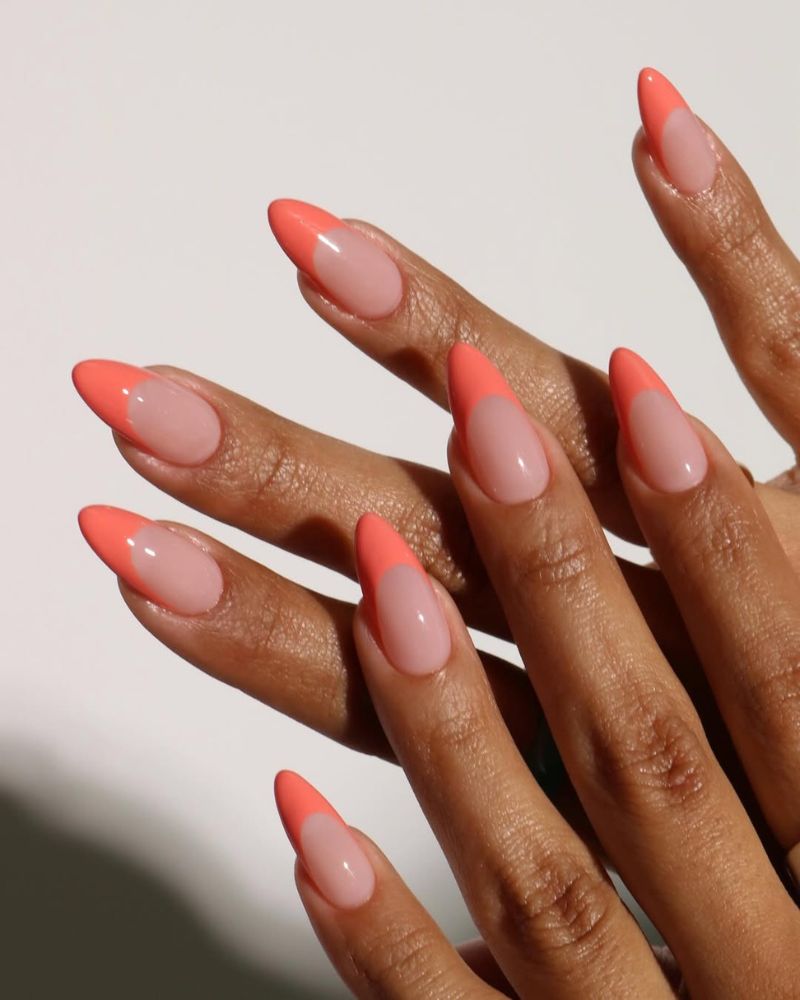 almond nails with coral French tips on a sheer nude base for summer
