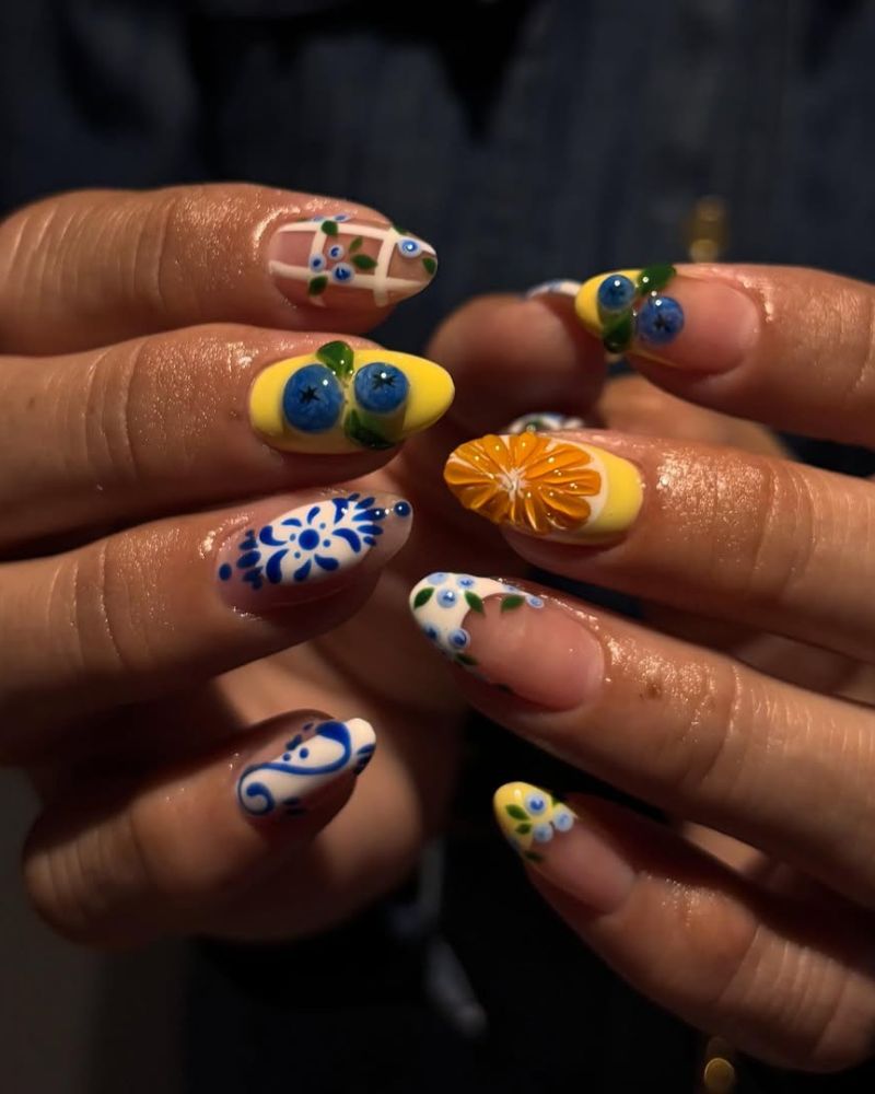 Mediterranean-inspired nail art with 3D blueberries, Delft tile painting, and orange slice
