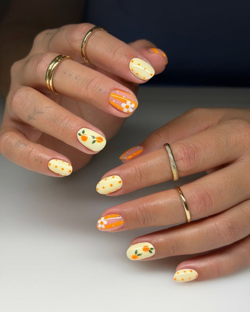 short oval nails in butter yellow with retro orange stripes, polka dots, and mandarin art
