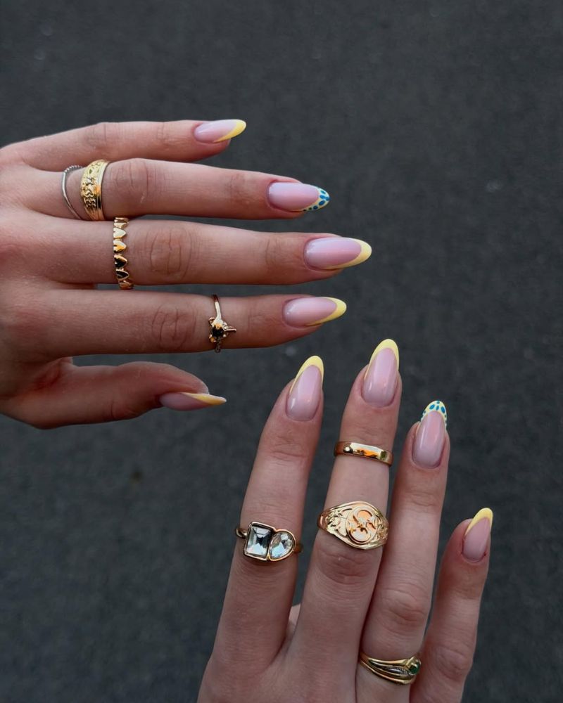 lemon yellow french tip nails with blue polka dot accent nail on pink nude base