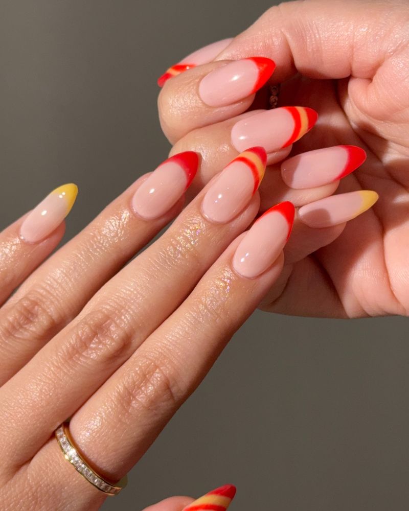 red and yellow french tip nails on almond nude base
