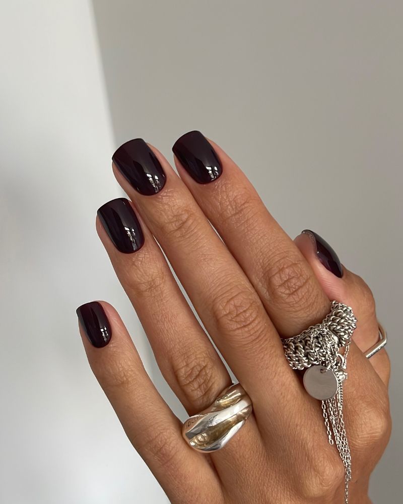 near-black dark cherry burgundy short round nails close-up grey background