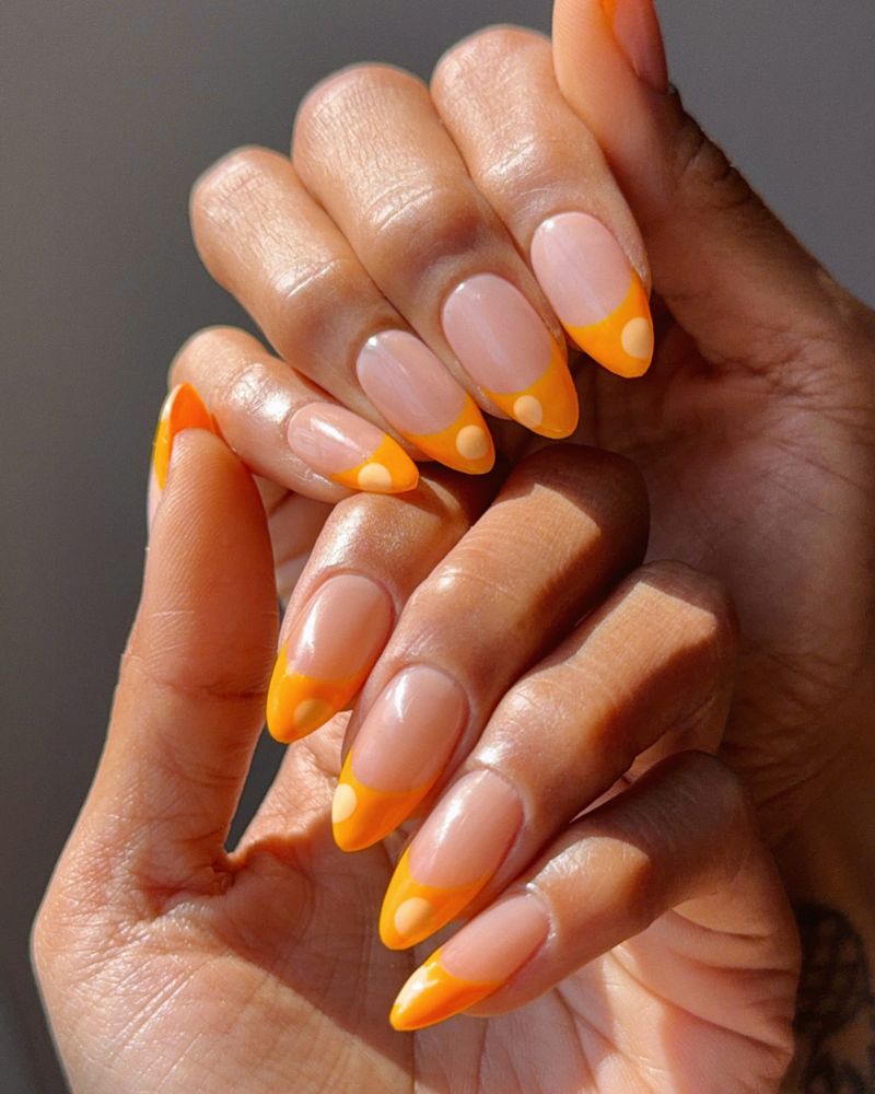 bright orange french tip on sheer almond nails with polka dot detail