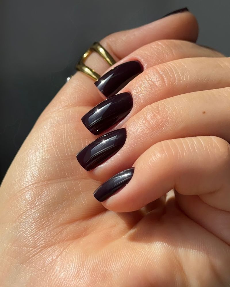 long coffin nails in near black espresso dark brown ultra glossy gold ring dark grey background