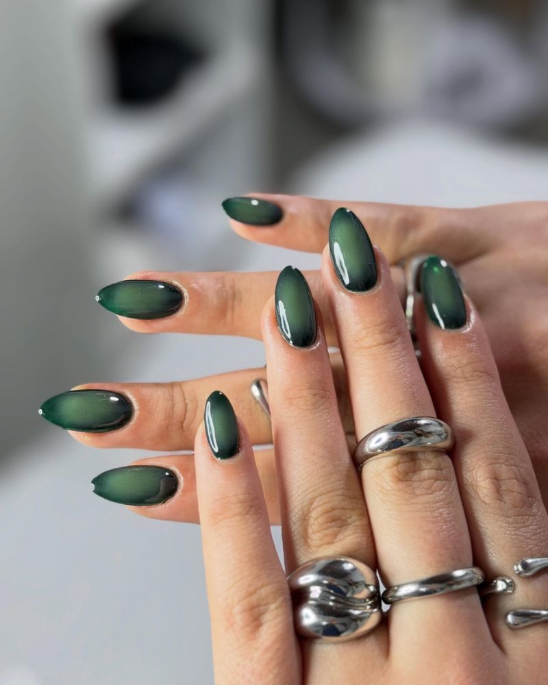 dark hunter green cat eye aura on almond nails with chunky silver rings