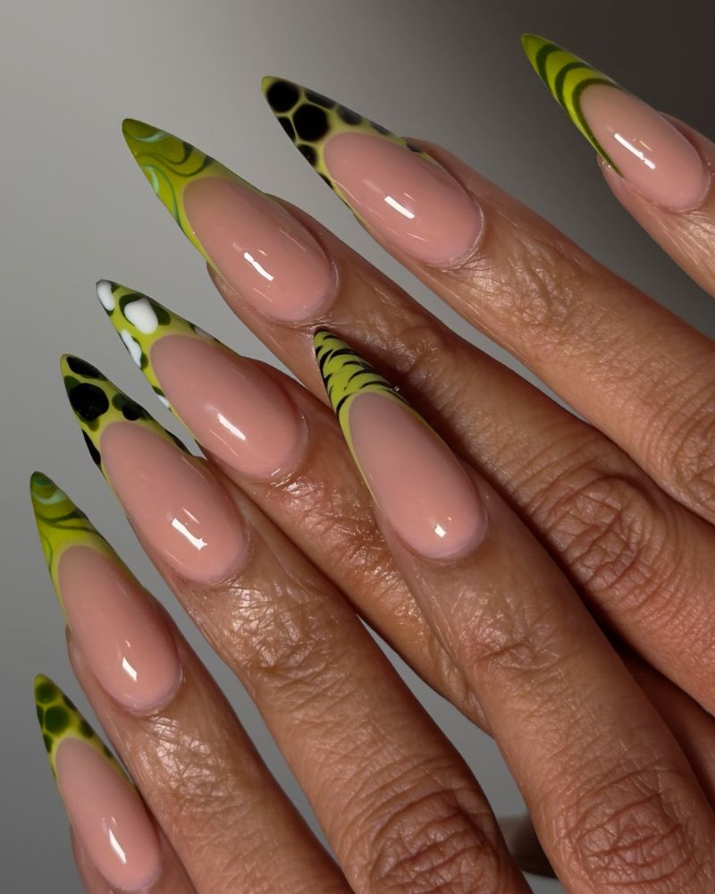 lime green abstract graphic tips with black swirl pattern on long stiletto nails