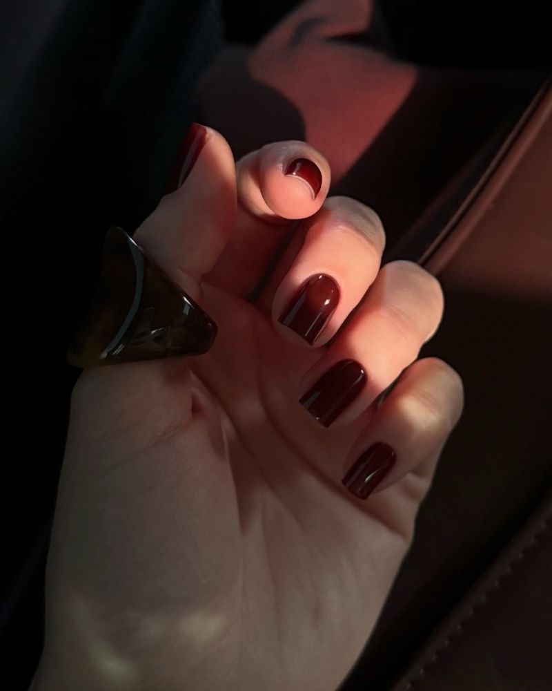 dark cherry crimson short square nails in warm-lit editorial car shot
