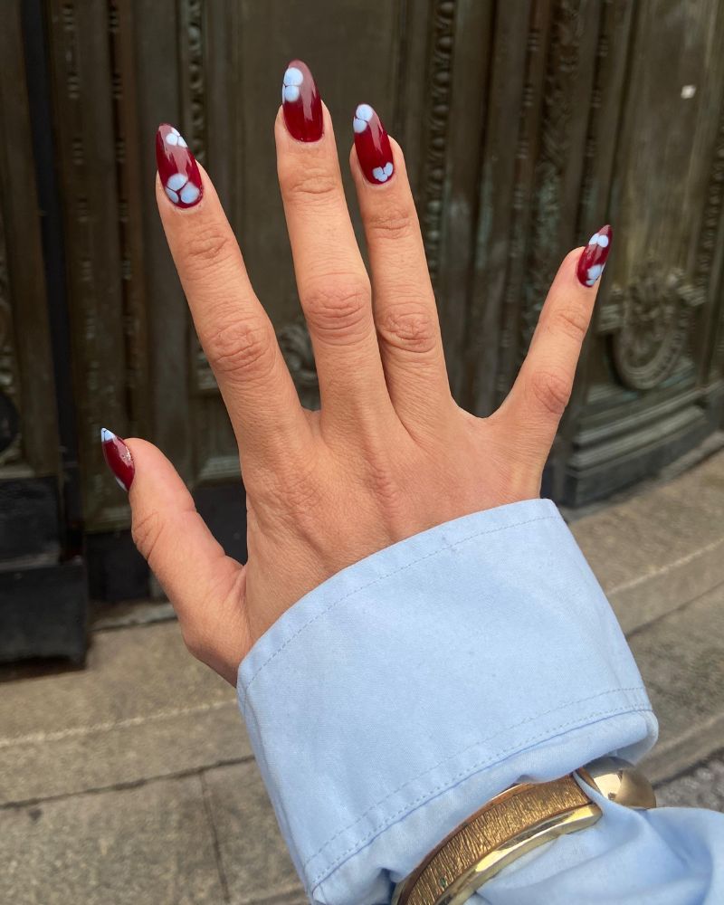 dark cranberry almond nails with tiny blue painted flower petal art