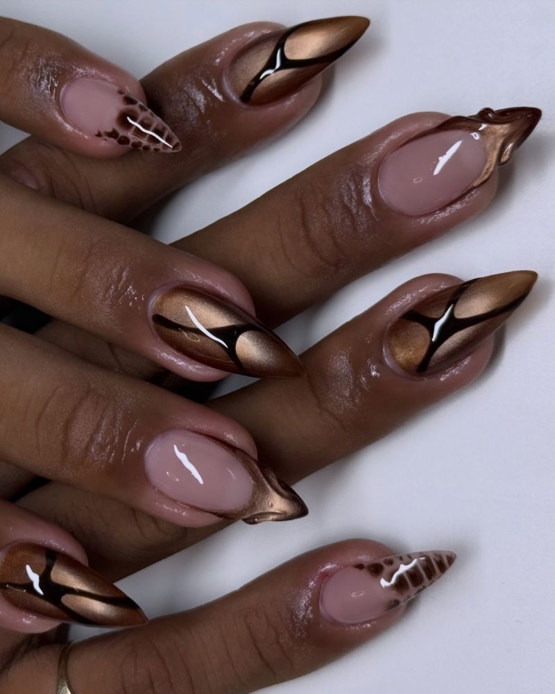 editorial stiletto nails on deep brown skin nude base with abstract geometric chocolate and bronze sections outlined in black at the tips