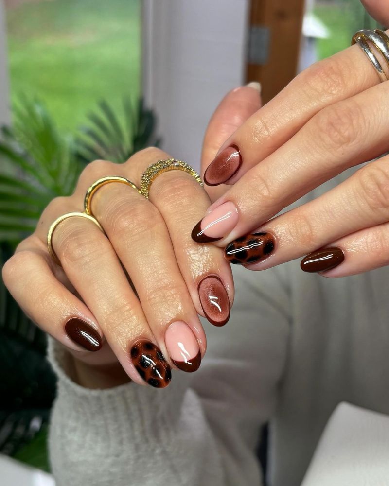 short oval nails mixed set dark chocolate espresso solid and nude nail and warm amber leopard print accent nails gold rings white knit sweater garden plants background