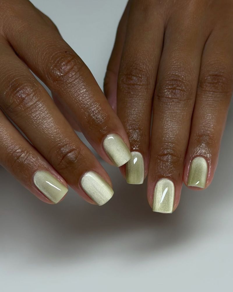short square pale gold-green jelly nails with a pearlescent cat eye shift