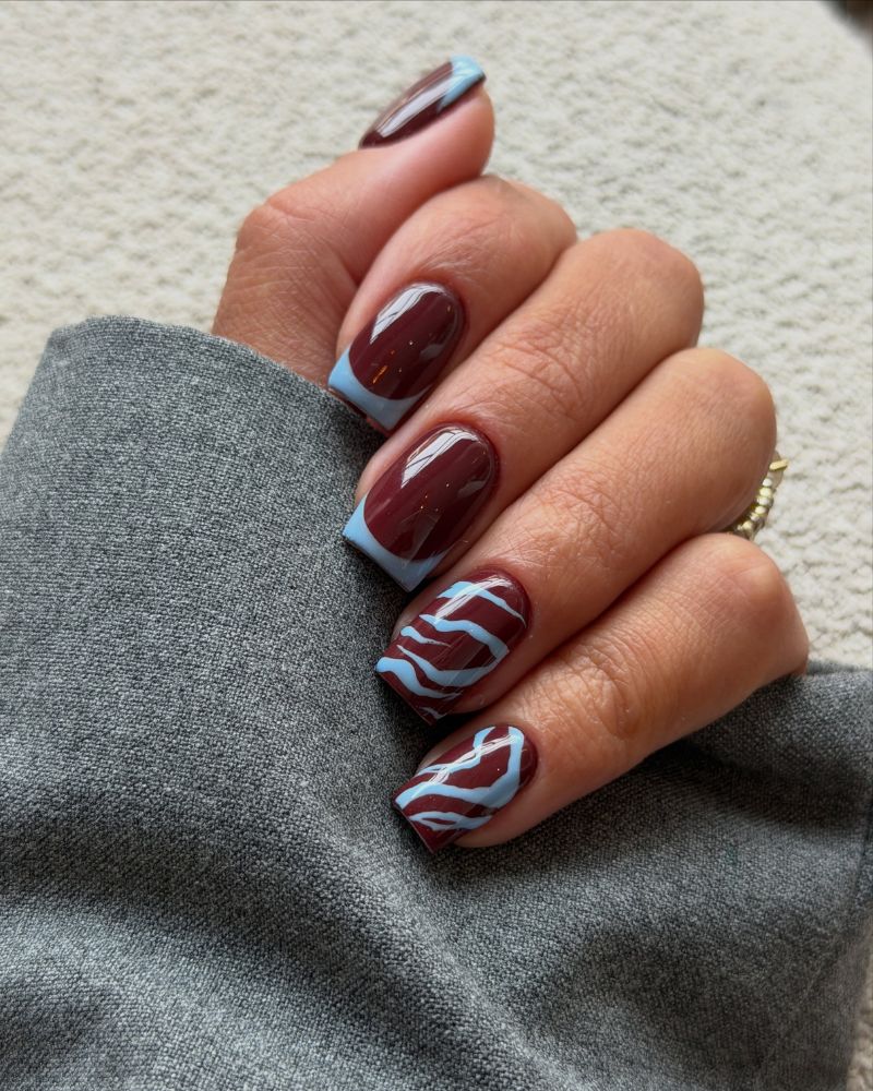 dark red short square nails with baby blue zebra stripe and blue french outline
