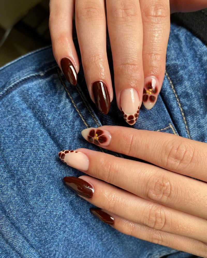medium long almond nails mixed set dark wine espresso solid nude nails with large dark brown flower art tiny gold centers and nude nails with scattered brown dots blue denim both hands