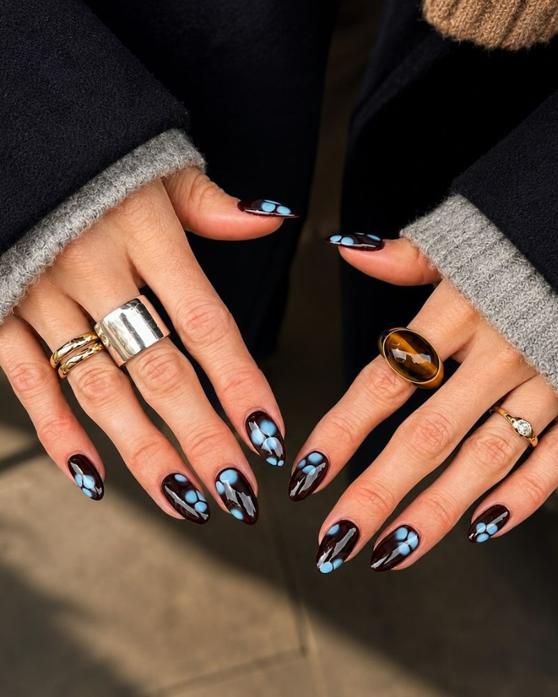 near-black dark base medium almond nails with baby blue blob floral designs