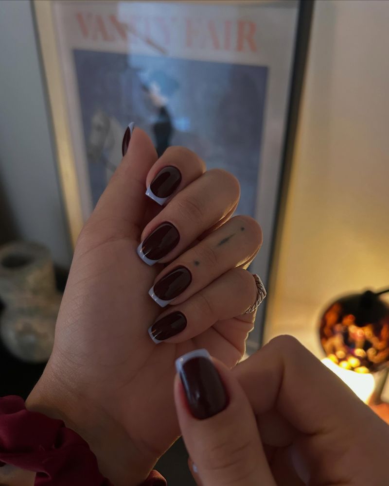 short oval deep wine brown nails with white french tips candlelit warm setting vanity fair poster twist ring