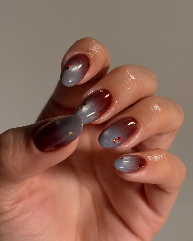 burgundy jelly nails with a grey-blue aura center and scattered crystals
