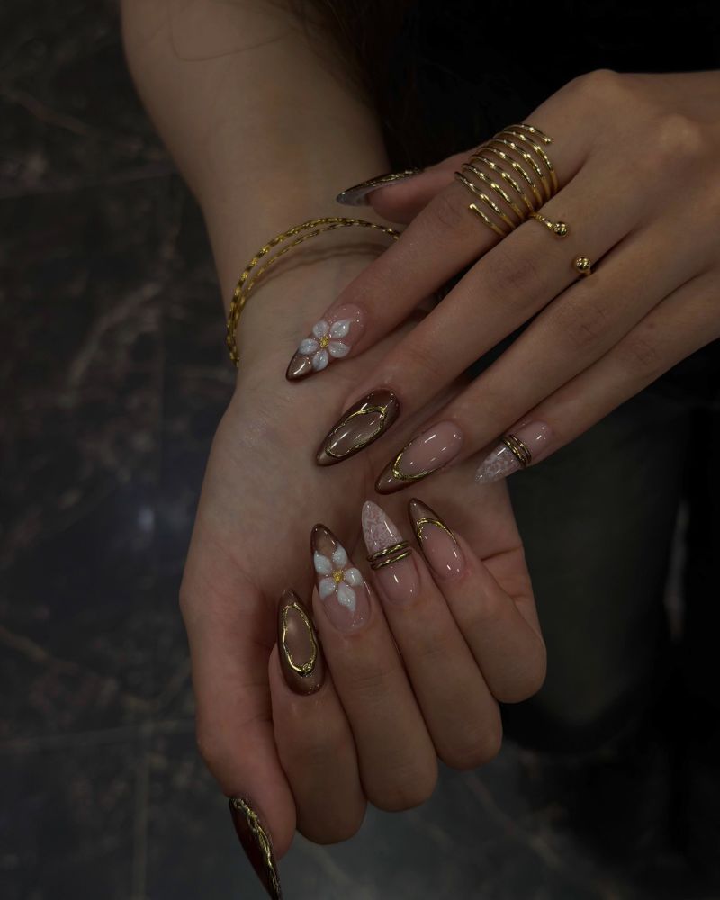dark chocolate brown stiletto nails with 3D white floral and gold frame accents